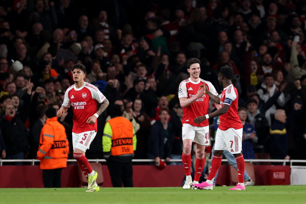 Declan Rice congratulates Bukayo Saka on the pitch at the Emirates as Piero Hincapie runs past them
