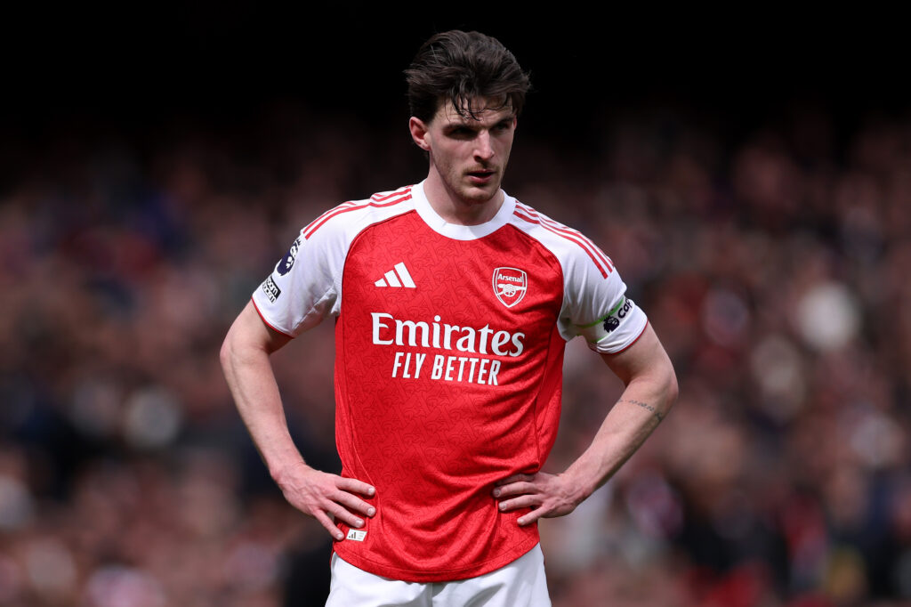 Declan Rice, in an Arsenal kit, stands with his hands on his hips