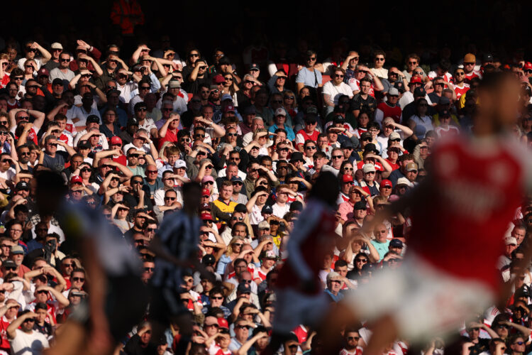 Arsenal fans watch a match at the Emirates, pictures of players are blurry in the foreground