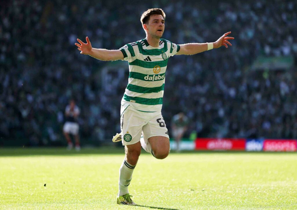 Kieran Tierney in a Celtic strip runs with his arms outstretched after scoring