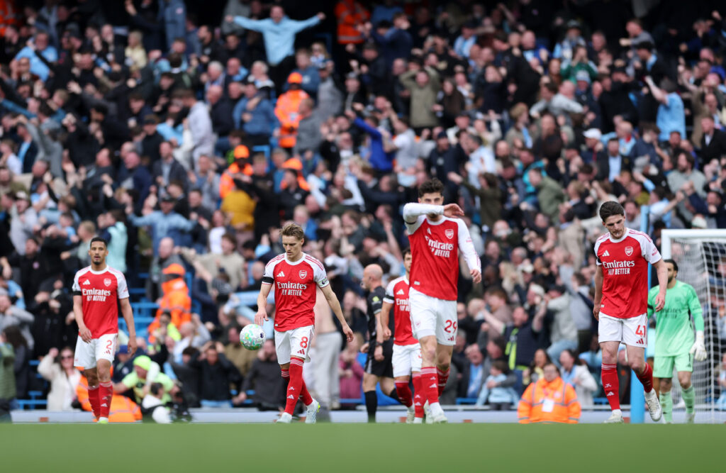 Dejected Arsenal players walk back to the half way line after Manchester City score