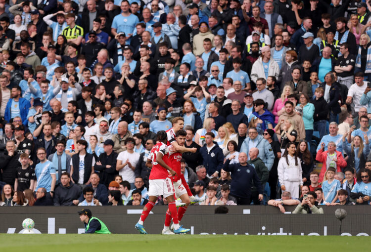 Martin Odegaard jumps on Kai Havertz's back after the German scored. Man City crowd is in the background