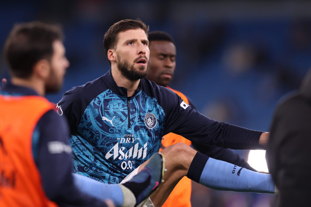 Ruben Dias warms up, kicking his own hand with his right foot