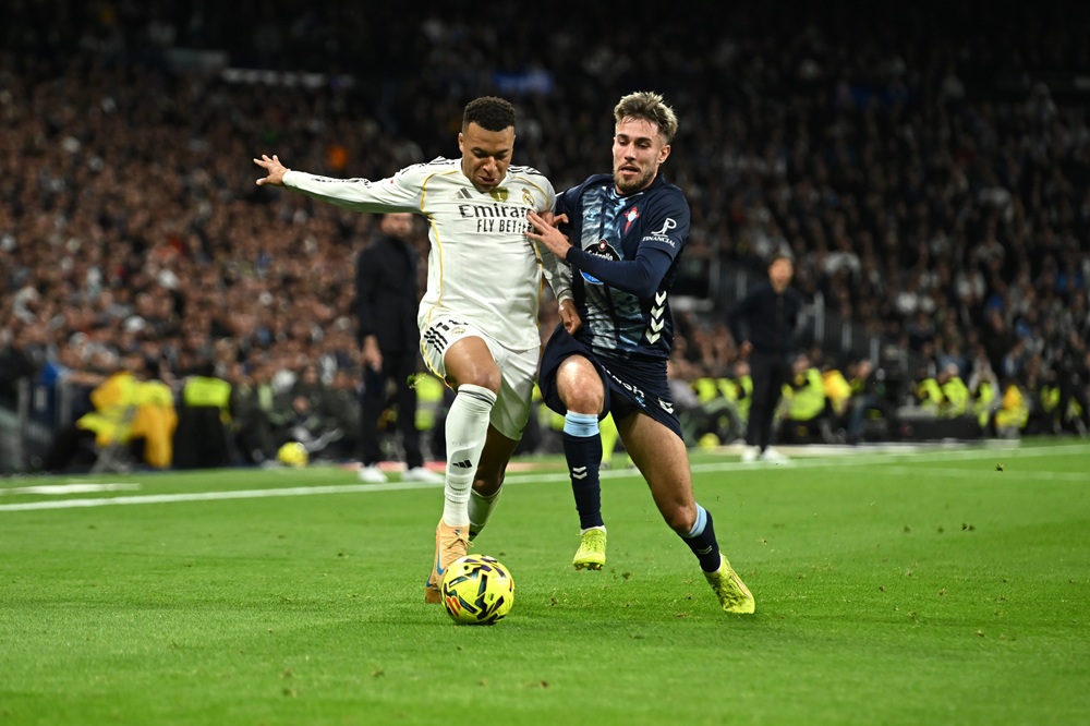 Kylian Mbappe of Real Madrid runs with the ball whilst under pressure from Oscar Mingueza of Celta Vigo during the LaLiga EA Sports match between Real Madrid CF and RC Celta de Vigo at Estadio Santiago Bernabeu on December 07, 2025 in Madrid, Spain. (Photo by Denis Doyle/Getty Images)