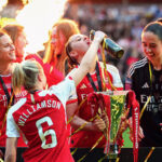 Leah Williamson of Arsenal pours a drink into the mouth of teammate Katie McCabe following the FA Women's Continental Tyres League Cup Final match between Arsenal and Chelsea at Molineux on March 31, 2024