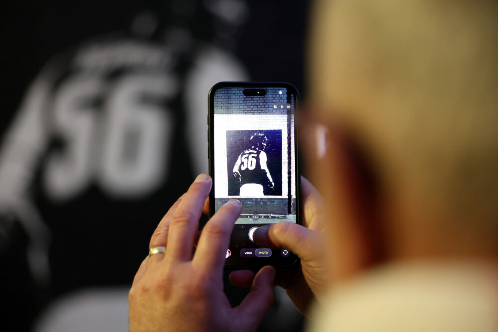 A detailed view of a mobile phone taking a photo of a Max Dowman mural prior to the UEFA Champions League 2025/26 Round of 16 Second Leg match betw...