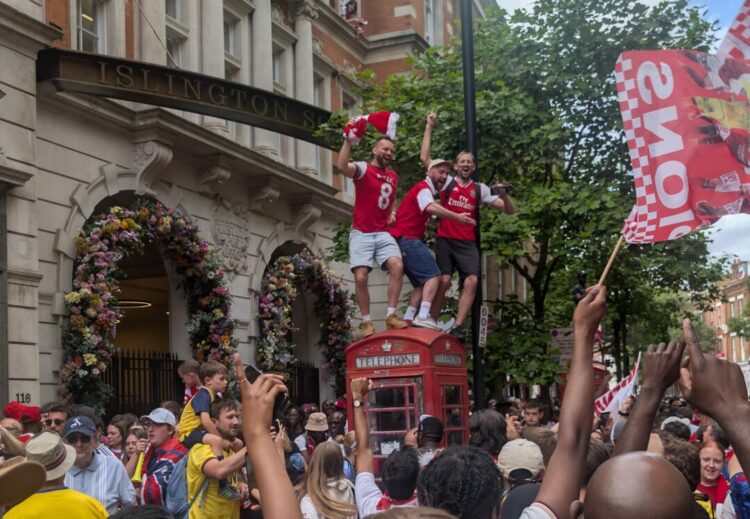 Three lunatics on a phonebox after Arsenal's Champions parade. Upper St, 31 May 2026