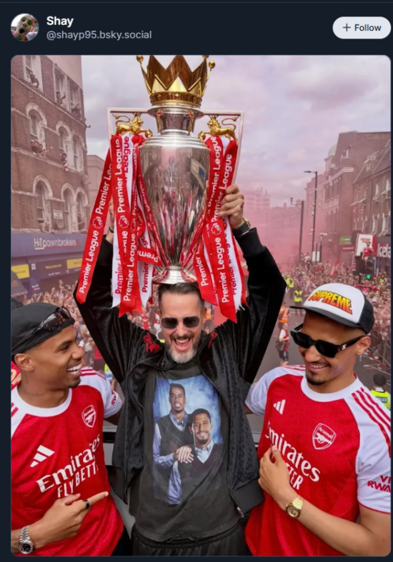Josh Kroenke holds the Premier League trophy on his head. William Saliba and Gabriel atand either side of him. He is wearing a meme tshirt of Gabriel and Saliba in argyle sweaters