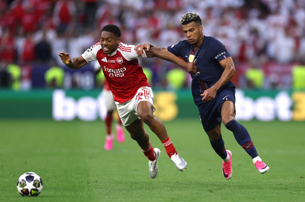Myles Lewis-Skelly of Arsenal runs with the ball while under pressure from Desire Doue of Paris Saint-Germain during the UEFA Champions League Final 2026 match between Paris Saint-Germain and Arsenal FC at Puskas Arena on May 30, 2026