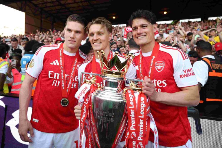 Viktor Gyoekeres, Martin Odegaard and Christian Norgaard of Arsenal pose for a photograph the Premier League trophy as players of Arsenal celebrate...