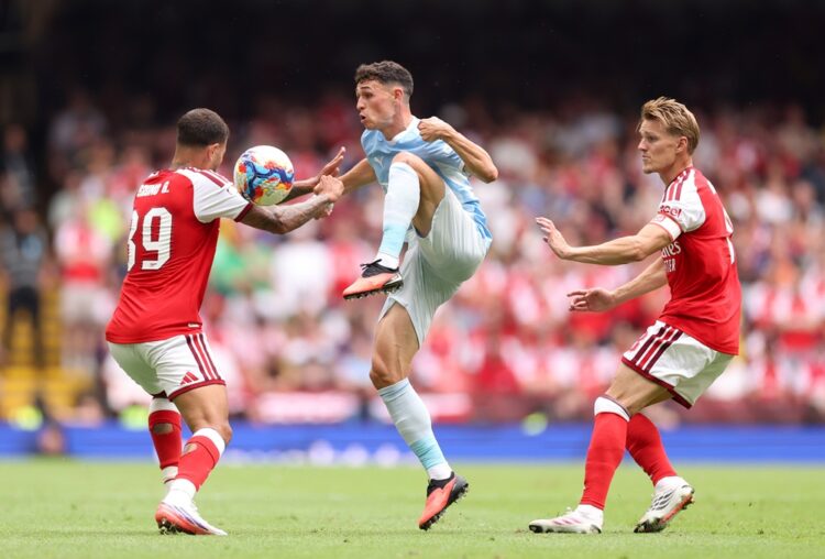 Phil Foden of Manchester City is challenged by Bruno Guimaraes and Martin Odegaard of Arsenal during the 2026 FA Community Shield match between Ars...