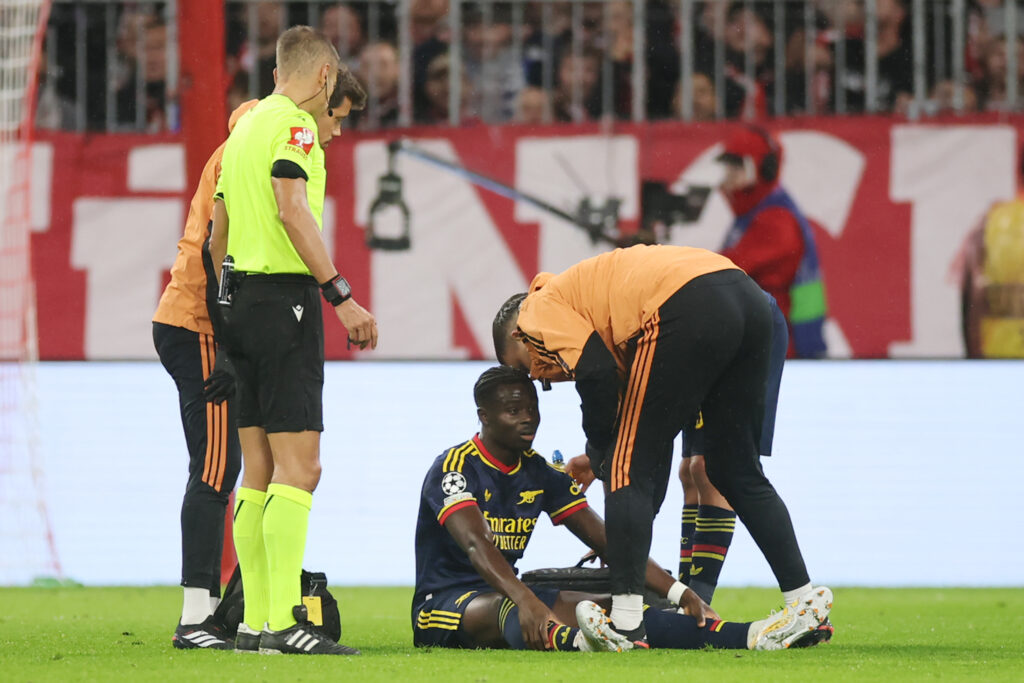 MUNICH, GERMANY - OCTOBER 21: Bukayo Saka of Arsenal receives medical attention after sustaining an injury during the UEFA Champions League 2026/27 League Phase MD3 match between FC Bayern München and Arsenal FC at Football Arena Munich on October 21, 2026 in Munich, Germany. (Photo by Alex Grimm/Getty Images)