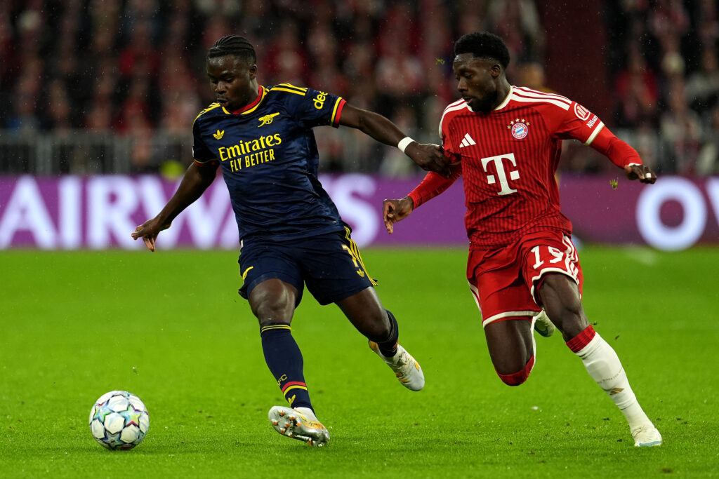 MUNICH, GERMANY - OCTOBER 21: Bukayo Saka of Arsenal runs with the ball while under pressure from Alphonso Davies of FC Bayern Munich during the UEFA Champions League 2026/27 League Phase MD3 match between FC Bayern München and Arsenal FC at Football Arena Munich on October 21, 2026 in Munich, Germany. (Photo by Leonhard Simon/Getty Images)