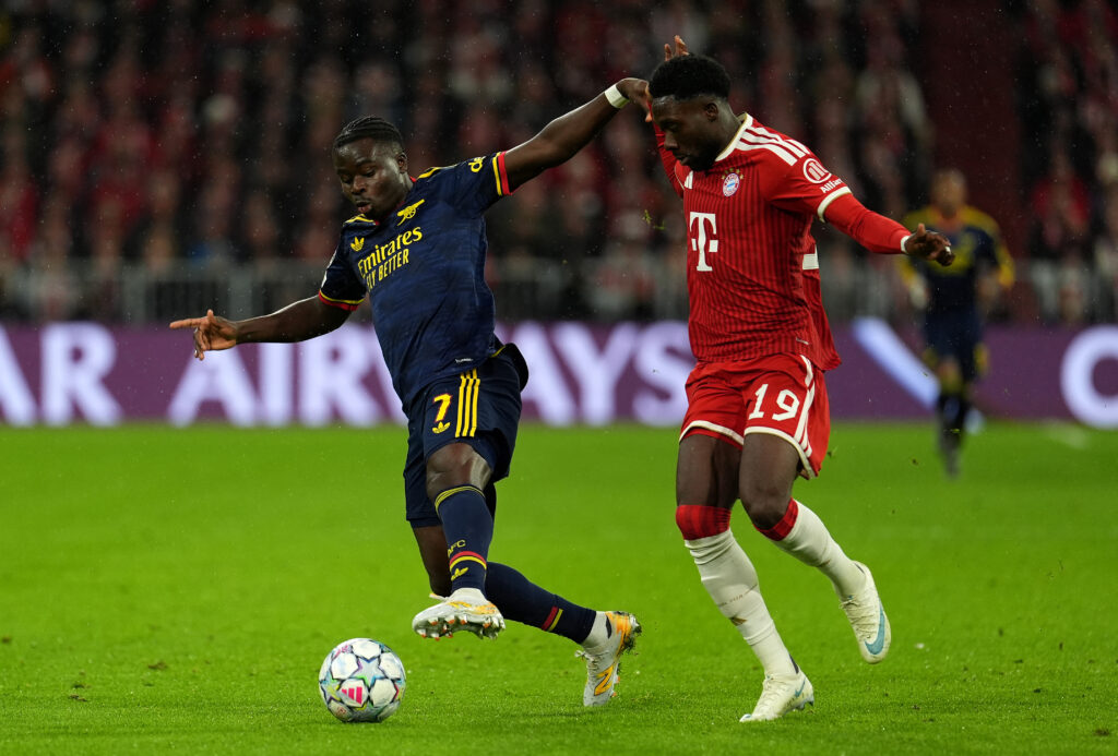 MUNICH, GERMANY - OCTOBER 21: Bukayo Saka of Arsenal runs with the ball while under pressure from Alphonso Davies of FC Bayern Munich during the UEFA Champions League 2026/27 League Phase MD3 match between FC Bayern München and Arsenal FC at Football Arena Munich on October 21, 2026 in Munich, Germany. (Photo by Leonhard Simon/Getty Images)