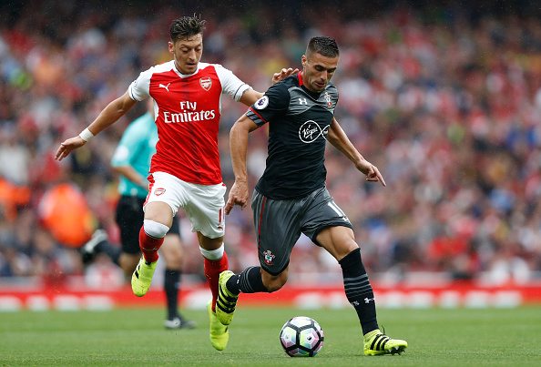 LONDON, ENGLAND - SEPTEMBER 10: Dusan Tadic of Southampton (R) is tugged by Mesut Ozil of Arsenal (L) during the Premier League match between Arsenal and Southampton at Emirates Stadium on September 10, 2016 in London, England. (Photo by Clive Rose/Getty Images)