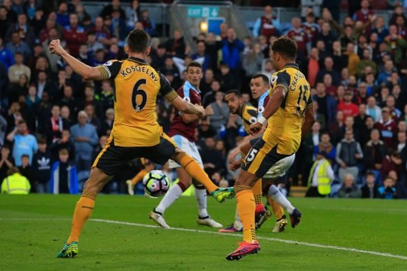 Arsenal's French defender Laurent Koscielny (L) deflects the ball into the net from English midfielder Alex Oxlade-Chamberlain's shot as Arsenal score a last minute winning goal during the English Premier League football match between Burnley and Arsenal at Turf Moor in Burnley, north west England on October 2, 2016. Arsenal won the game 1-0. / AFP / Lindsey PARNABY / RESTRICTED TO EDITORIAL USE. No use with unauthorized audio, video, data, fixture lists, club/league logos or 'live' services. Online in-match use limited to 75 images, no video emulation. No use in betting, games or single club/league/player publications. / (Photo credit should read LINDSEY PARNABY/AFP/Getty Images)