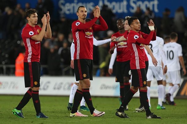 Manchester United's Swedish striker Zlatan Ibrahimovic (C) and Manchester United's English midfielder Jesse Lingard applaud the fans following the English Premier League football match between Swansea City and Manchester United at The Liberty Stadium in Swansea, south Wales on November 6, 2016. Manchester United won the match 3-1. / AFP / GEOFF CADDICK / RESTRICTED TO EDITORIAL USE. No use with unauthorized audio, video, data, fixture lists, club/league logos or 'live' services. Online in-match use limited to 75 images, no video emulation. No use in betting, games or single club/league/player publications. / (Photo credit should read GEOFF CADDICK/AFP/Getty Images)