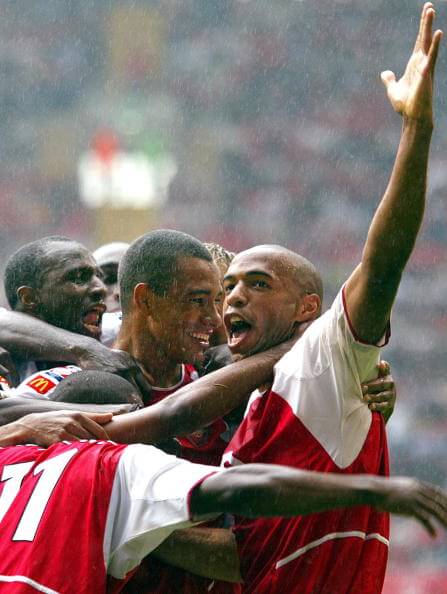 CARDIFF, UNITED KINGDOM: Arsenal's French forward Thierry Henry (R) and captain Patrick Vieira (L) congratulate Brazilian player Gilberto Silva (C) on his goal during the FA Community Shield match against Liverpool at the Millenium stadium in Cardiff, 11 August 2002. (Odd Andersen/AFP/Getty Images)