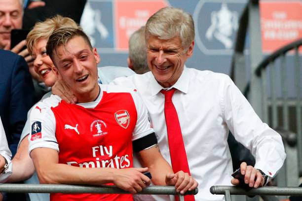 Arsenal's French manager Arsene Wenger (R) and Arsenal's German midfielder Mesut Ozil smile as Arsenal players celebrate their victory over Chelsea in the English FA Cup final football match between Arsenal and Chelsea at Wembley stadium in London on May 27, 2017. (ADRIAN DENNIS/AFP/Getty Images)