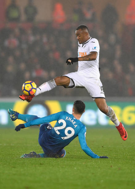 SWANSEA, WALES - JANUARY 30: Granit Xhaka of Arsenal tackles Jordan Ayew of Swansea City during the Premier League match between Swansea City and Arsenal at Liberty Stadium on January 30, 2018 in Swansea, Wales. (Photo by Stu Forster/Getty Images)