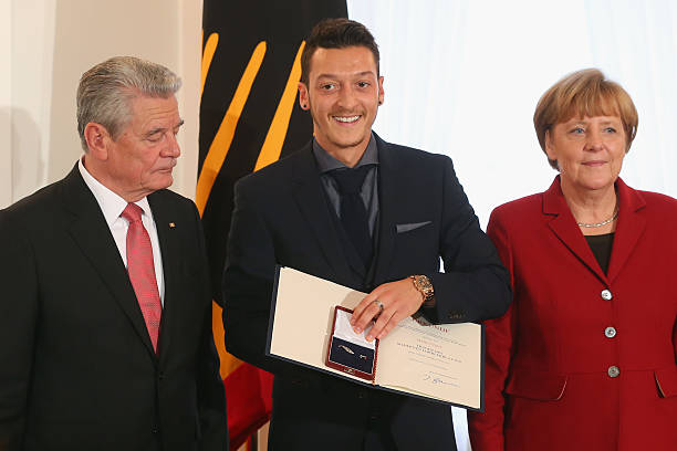 ERLIN, GERMANY - NOVEMBER 10: Germanys Federal President Joachim Gauck (L) and German Chancellor Angela Merkel awards Mesut Oezil of the German national football team with the Silbernes Lorbeerblatt for winning the FIFA World Cup 2014 title during the Silbernes Lorbeerblatt Award Ceremony at Schloss Bellevue Palace on November 10, 2014 in Berlin, Germany. (Photo by Alexander Hassenstein/Bongarts/Getty Images)