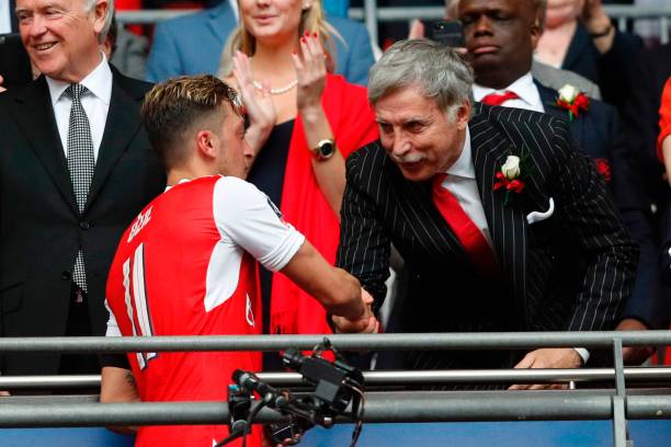 Arsenal's US owner Stan Kroenke shakes hands with Arsenal's German midfielder Mesut Ozil (2nd L) as Arsenal players celebrate their victory over Chelsea in the English FA Cup final football match between Arsenal and Chelsea at Wembley stadium in London on May 27, 2017. Aaron Ramsey scored a 79th-minute header to earn Arsenal a stunning 2-1 win over Double-chasing Chelsea on Saturday and deliver embattled manager Arsene Wenger a record seventh FA Cup. / AFP PHOTO / Adrian DENNIS 