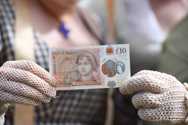 People in period costume pose with on the Bank of England's new ten pound notes, featuring author Jane Austen, during its launch at Winchester Cathedral in Winchester, southern England, on July 18, 2017. Two hundred years after Jane Austen's death, Britain is celebrating one of its best-loved authors, who combined romance with biting social commentary that still speaks to fans around the world. Austen is buried in the cathedral in Winchester, where she died. / AFP PHOTO / POOL AND AFP PHOTO / Chris J Ratcliffe (Photo credit should read CHRIS J RATCLIFFE/AFP/Getty Images)