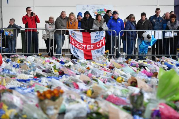 Supporters pause at the pile of floral tributes outside Leicester City Football Club's King Power Stadium in Leicester, eastern England, on October 28, 2018 after a helicopter belonging to the club's Thai chairman Vichai Srivaddhanaprabha crashed outside the stadium the night before. - Leicester City's charismatic Thai chairman was the subject of growing concerns on October 28 after a helicopter belonging to the billionaire crashed and burst into flames in the stadium car park shortly after taking off from the club's pitch following the match against West Ham United on October 27. There was no confirmation whether London-based Vichai Srivaddhanaprabha, who frequently flies to and from Leicester's home games by helicopter, was on board the aircraft which appeared to develop mechanical problems. (Photo by Ben STANSALL / AFP) (Photo credit should read BEN STANSALL/AFP/Getty Images)