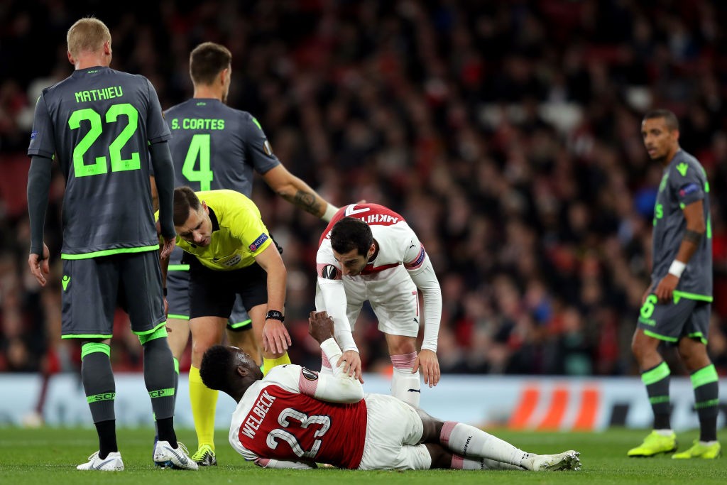 LONDON, ENGLAND - NOVEMBER 08: Referee Gediminas Mazeika and Henrikh Mkhitaryan of Arsenal stand over Danny Welbeck of Arsenal as he is injured during the UEFA Europa League Group E match between Arsenal and Sporting CP at Emirates Stadium on November 8, 2018 in London, United Kingdom. (Photo by Richard Heathcote/Getty Images)