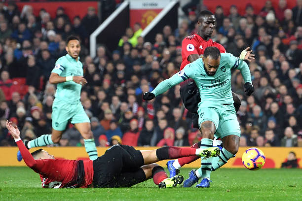 MANCHESTER, ENGLAND - DECEMBER 05: Alexandre Lacazette of Arsenal scores his team's second goal as he is challenged by Marcos Rojo of Manchester United during the Premier League match between Manchester United and Arsenal FC at Old Trafford on December 5, 2018 in Manchester, United Kingdom. (Photo by Michael Regan/Getty Images)