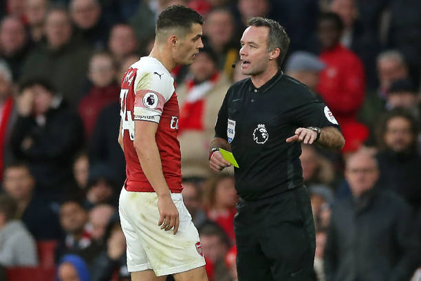 English referee Paul Tierney shows a yellow card to Arsenal's Swiss midfielder Granit Xhaka (L) during the English Premier League football match between Arsenal and Huddersfield Town at the Emirates Stadium in London on December 8, 2018. (Photo by Daniel LEAL-OLIVAS / AFP) 