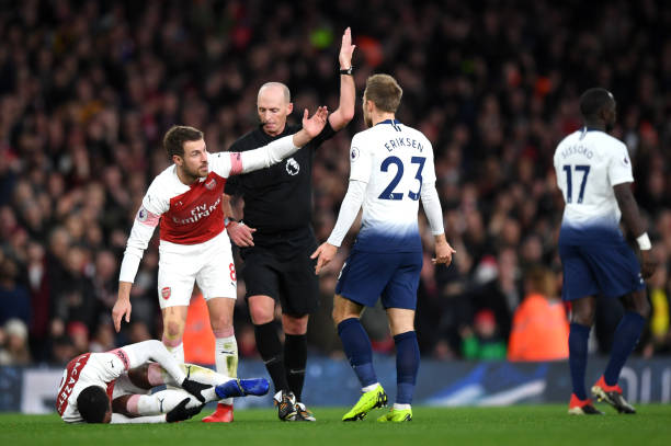 LONDON, ENGLAND - DECEMBER 02: Match Referee Mike Dean gestures as Aaron Ramsey consults teammate Alexandre Lacazette of Arsenal after a foul during the Premier League match between Arsenal FC and Tottenham Hotspur at Emirates Stadium on December 1, 2018 in London, United Kingdom. (Photo by Shaun Botterill/Getty Images)