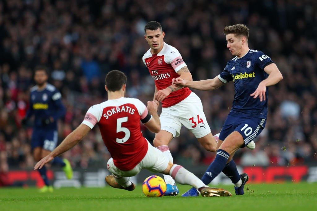 LONDON, ENGLAND - JANUARY 01: Tom Cairney of Fulham shoots while under pressure from Sokratis Papastathopoulos of Arsenal and Granit Xhaka of Arsenal during the Premier League match between Arsenal FC and Fulham FC at Emirates Stadium on January 1, 2019 in London, United Kingdom. (Photo by Catherine Ivill/Getty Images)