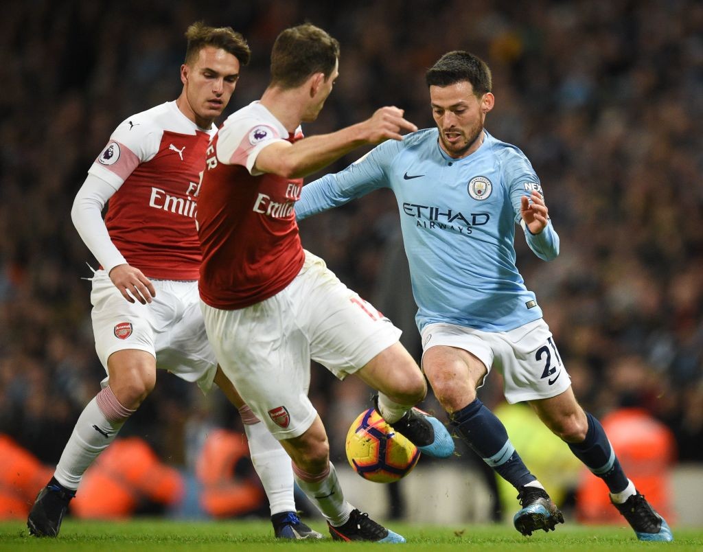 Manchester City's Spanish midfielder David Silva (R) takes on Arsenal's Swiss defender Stephan Lichtsteiner (C) during the English Premier League football match between Manchester City and Arsenal at the Etihad Stadium in Manchester, north west England, on February 3, 2019. (Photo by OLI SCARFF / AFP / Getty Images)