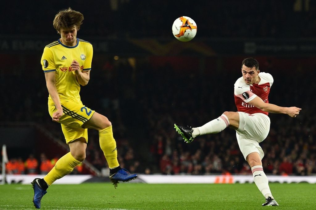 BATE Borisov's Belarusian midfielder Dmitri Baga (L) takes evasive action as Arsenal's Swiss midfielder Granit Xhaka shoots over during the UEFA Europa League round of 32, 2nd leg football match between Arsenal and Bate Borisov at the Emirates stadium in London on February 21, 2019. (Photo by Glyn KIRK / AFP / Getty Images)