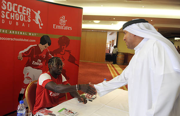 Arsenal's French defender Bacary Sagna shakes hands with an unidentified Emirati man during his visit to the Arsenal Soccer School in the Gulf emirate of Dubai on November 12, 2011.   AFP PHOTO/STR