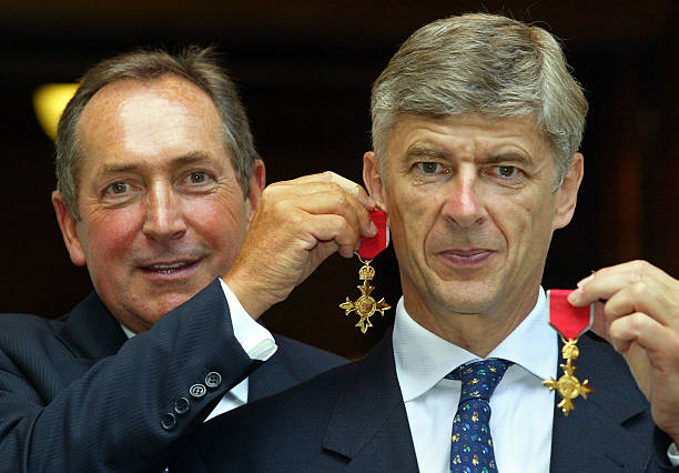 Gerard Houllier (L) of Liverpool holds his OBE medal as an earring on long-term friend and fellow manager Arsene Wenger of Arsenal, after being awarded their OBE medals at The Foreign Office in London 09 July 2003. The honor awarded by Foreign Secretary Jack Straw, is that of an officer in the Most Excellent Order of the British Empire. The British honors are awarded on merit for exceptional achievement of service to British interests. AFP PHOTO Adrian DENNIS / WPA POOL