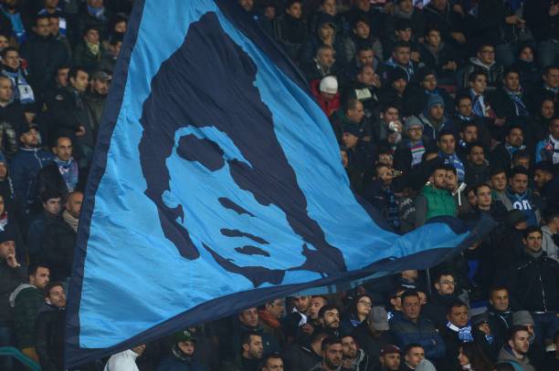 Napoli's fans wave a giant flag showing former Argentinian soccer star Diego Maradona prior the UEFA Champions League group F football match between SSC Napoli and Arsenal FC at the San Paolo Stadium in Naples on December 11, 2013. AFP PHOTO / GABRIEL BOUYS (Photo by GABRIEL BOUYS / AFP)