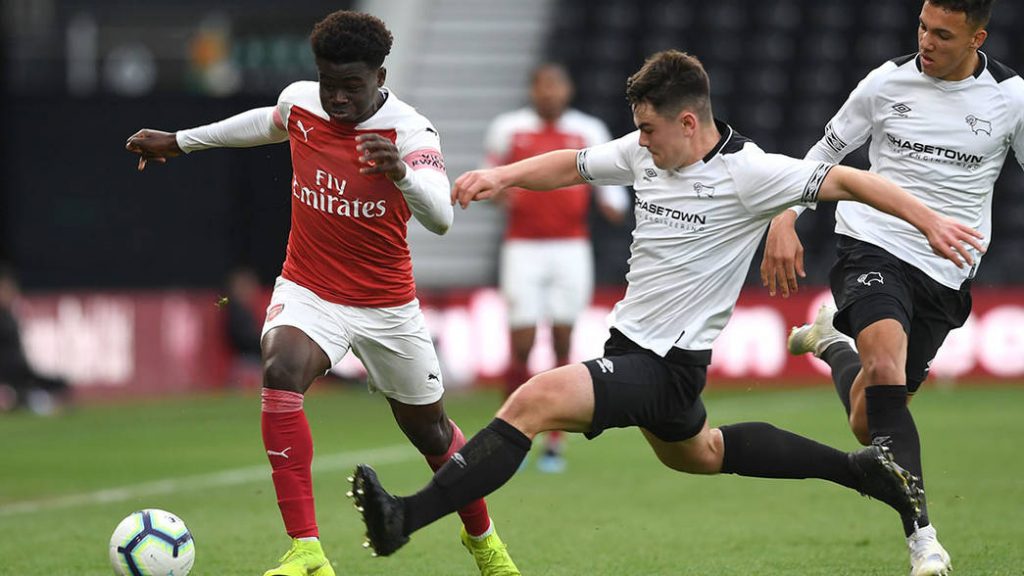 DERBY, ENGLAND - MAY 07: Bukayo Saka of Arsenal is fouled by Eiran Cashin of Derby during the match between Derby County U18 and Arsenal U18 in the U18 Premier League Play Off at Pride Park on May 7, 2019 in Derby, England. (Photo by David Price/Arsenal FC via Getty Images)