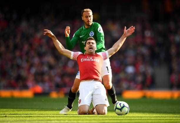 LONDON, ENGLAND - MAY 05: Sokratis Papastathopoulos of Arsenal is challenged by Glenn Murray of Brighton and Hove Albion during the Premier League match between Arsenal FC and Brighton & Hove Albion at Emirates Stadium on May 05, 2019 in London, United Kingdom. (Photo by Clive Mason/Getty Images)