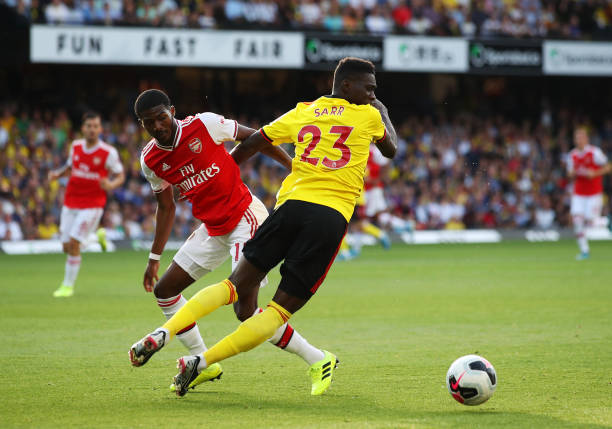 WATFORD, ENGLAND - SEPTEMBER 15:  Ismaila Sarr of Watford is challenged by Ainsley Maitland-Niles of Arsenal during the Premier League match between Watford FC and Arsenal FC at Vicarage Road on September 15, 2019 in Watford, United Kingdom. (Photo by Marc Atkins/Getty Images)