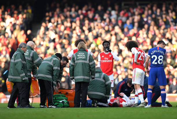 LONDON, ENGLAND - DECEMBER 29: Callum Chambers of Arsenal is given treatment following an injury during the Premier League match between Arsenal FC and Chelsea FC at Emirates Stadium on December 29, 2019 in London, United Kingdom. (Photo by Shaun Botterill/Getty Images)