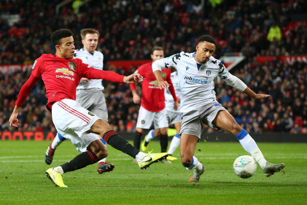 MANCHESTER, ENGLAND - DECEMBER 18: Mason Greenwood of Manchester United shoots while challenged by Cohen Bramall of Colchester United during the Carabao Cup Quarter Final match between Manchester United and Colchester United at Old Trafford on December 18, 2019 in Manchester, England. (Photo by Alex Livesey/Getty Images)