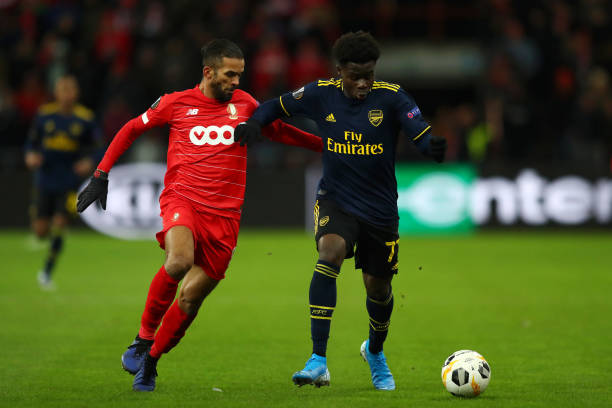 LIEGE, BELGIUM - DECEMBER 12: Bukayo Saka of Arsenal battles for possession with Mehdi Carcela of Standard Liege during the UEFA Europa League group F match between Standard Liege and Arsenal FC at Stade Maurice Dufrasne on December 12, 2019 in Liege, Belgium. (Photo by Dean Mouhtaropoulos/Getty Images)