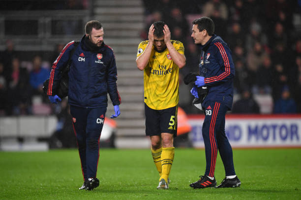 BOURNEMOUTH, ENGLAND - DECEMBER 26: Sokratis Papastathopoulos of Arsenal speaks to Dr Gary O'Driscoll, Team Doctor of Arsenal following a knock to his head during the Premier League match between AFC Bournemouth and Arsenal FC at Vitality Stadium on December 26, 2019 in Bournemouth, United Kingdom. (Photo by Dan Mullan/Getty Images)