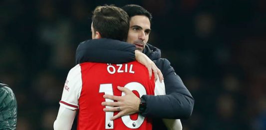 Arsenal's Spanish head coach Mikel Arteta (R) embraces Arsenal's German midfielder Mesut Ozil (L) on the pitch after the English Premier League football match between Arsenal and Manchester United at the Emirates Stadium in London on January 1, 2020. - Arsenal won the game 2-0. (Photo by Ian KINGTON / IKIMAGES / AFP)