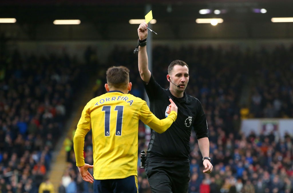 BURNLEY, ENGLAND - FEBRUARY 02: Match Referee Chris Kavanagh shows a yellow card to Lucas Torreira of Arsenal during the Premier League match between Burnley FC and Arsenal FC at Turf Moor on February 02, 2020, in Burnley, United Kingdom. (Photo by Alex Livesey/Getty Images)