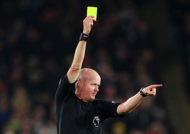 Referee Lee Mason awards a yellow card during the Premier League match between Sheffield United and Manchester City at Bramall Lane on January 21, 2020 in Sheffield, United Kingdom. 