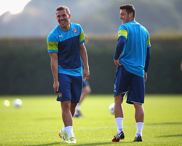 Lukas Podolski and Mesut Oezil of Arsenal (R) share a joke during an Arsenal training session ahead of their UEFA Champions League Group D match against Galatasaray at London Colney on September 30, 2014 in St Albans, England. 
