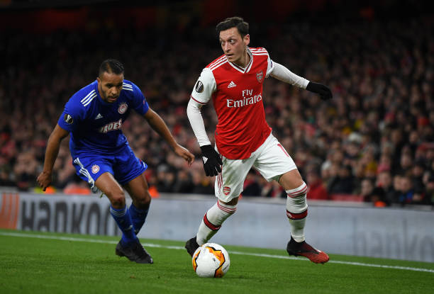 Mesut Ozil of Arsenal FC battles for possession with Youssef El Arabi of Olympiacos FC during the UEFA Europa League round of 32 second leg match between Arsenal FC and Olympiacos FC at Emirates Stadium on February 27, 2020 in London, United Kingdom.